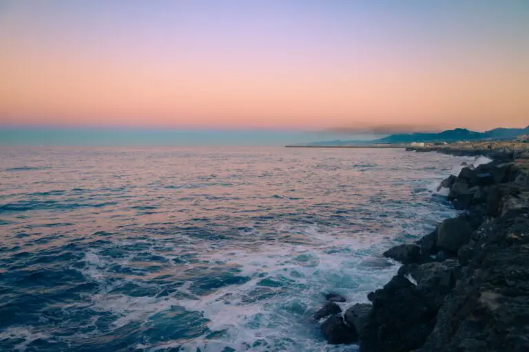 Waves splashing on rocky seashore illustrating how sedimentary rocks differ from igneous rocks